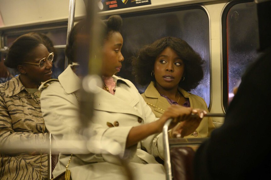 A still from the film Lovers Rock with actors Shaniqua Okwok and Amarah-Jae St. Aubyn sitting on a bus in the 70s