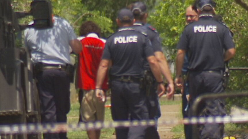 Police escort the man to an ambulance after he surrendered peacefully in Inala