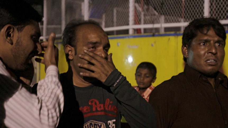 Men mourn the death of their relatives after a blast in Lahore