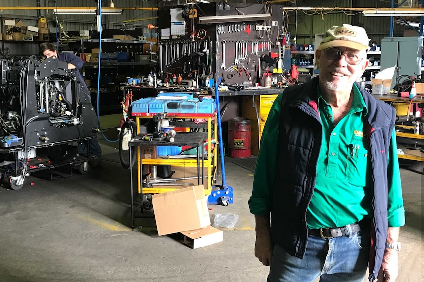 Garry Briggs stands in his workshop filled with tools and machinery.