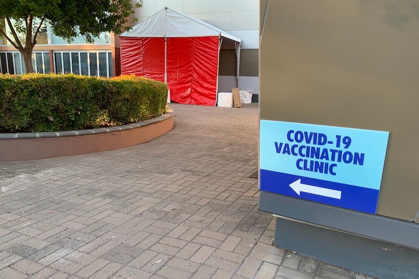A sign pointing to an orange tent and the opening of a vaccination clinic