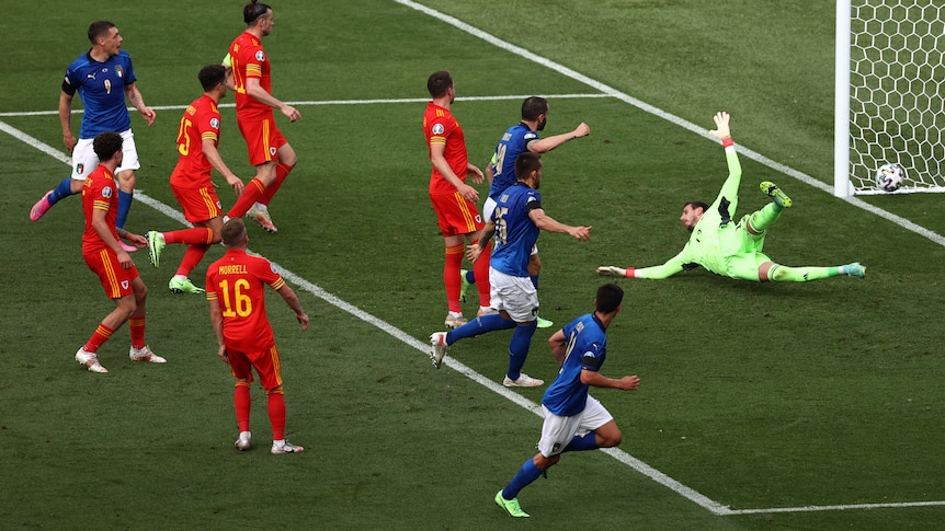 A group of Italy players watch as the ball runs past the Welsh keeper into the corner of the net at Euro 2020.