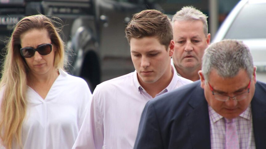 Timothy England walks with his parents and lawyer outside court in Cairns.
