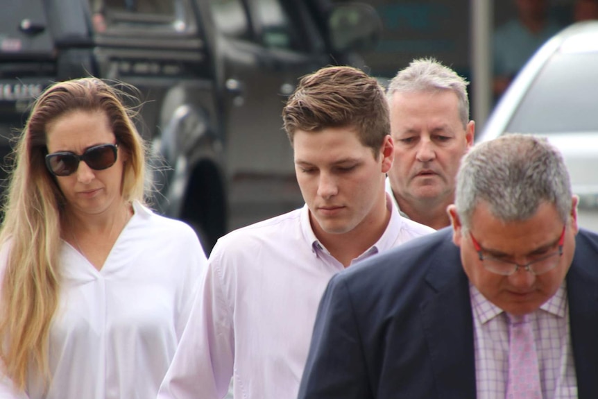 Timothy England walks with his parents and lawyer outside court in Cairns.