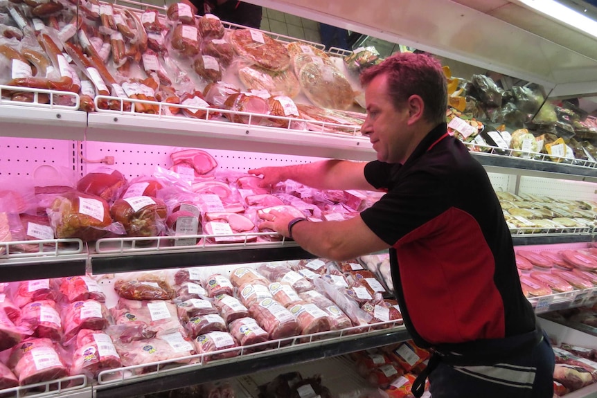 Andrew Kunde putting meat products on the shelf
