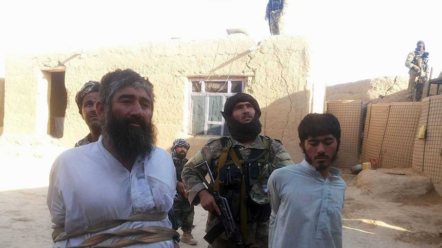 Two Taliban fighters arrested and tied up with rope outside a house in Afghanistan, 2016.