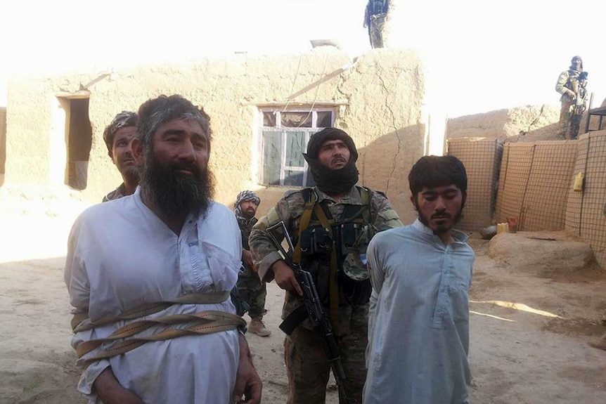 Two Taliban fighters arrested and tied up with rope outside a house in Afghanistan, 2016.