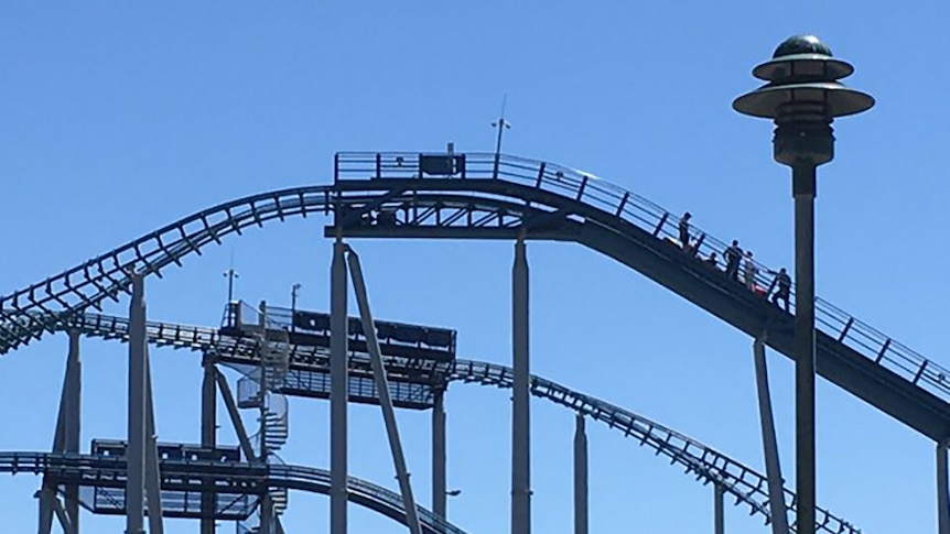 People standing around a stalled rollercoaster carriage