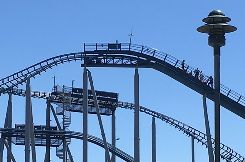 People standing around a stalled rollercoaster carriage