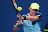 An Australian tennis player's arm muscles strain as he hits a backhand return during a match.