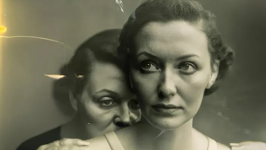An image of two women in black and white, the woman in front looks concerned to the side. Behind her an older woman.