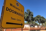 A roadside sign in the outback  reads 'Welcome to Doomadgee'.