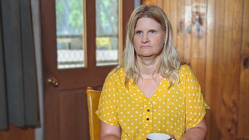 Shelley, a woman with blonde hair, a yellow top and a serious expression.