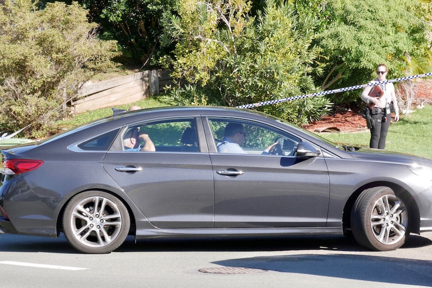 An unmarked police car driving under police tape