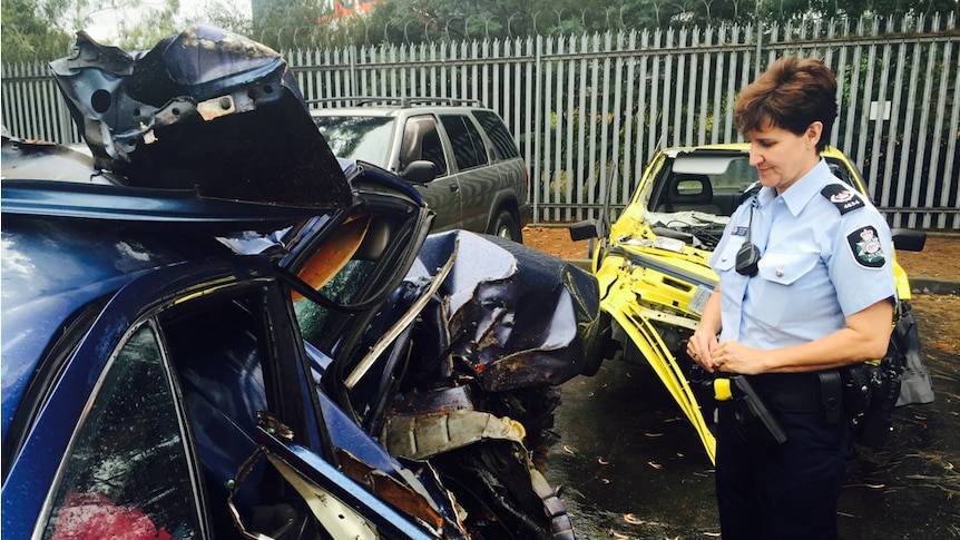 Station Sergeant Susan Ball stands beside a car wreck.