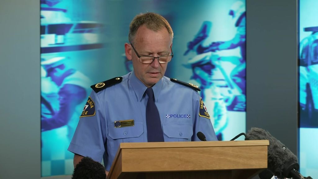 A police officer at a lectern speaking at a media conference.