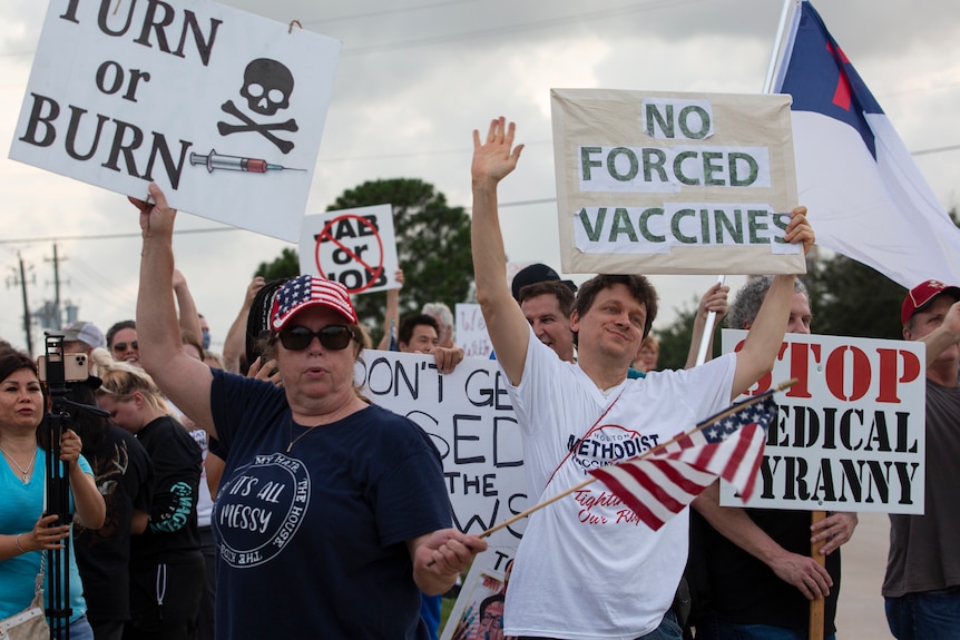 Protesters hold signs saying 'no forced vaccines' and 'stop medical tyranny' while waving the US flag 