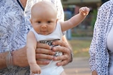 A baby looks excited at the camera.