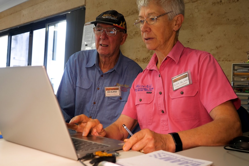 A man and woman look at a computer screen. 