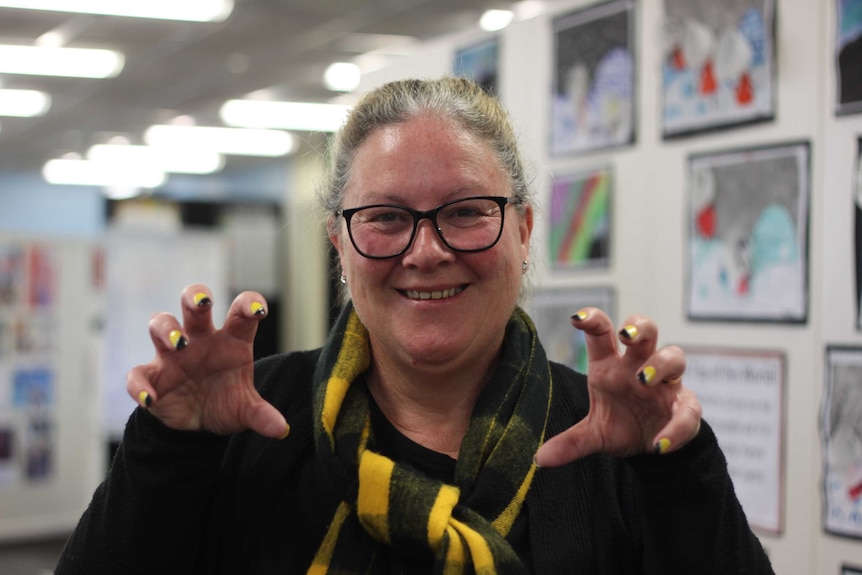 A Richmond fan has her nails painted in black and gold and is wearing a black and gold scarf