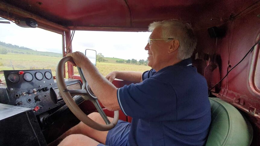 a man with white hair driving an old truck.