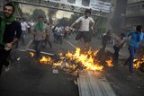 Iranian protesters jump and run over a fire during protests in Tehran