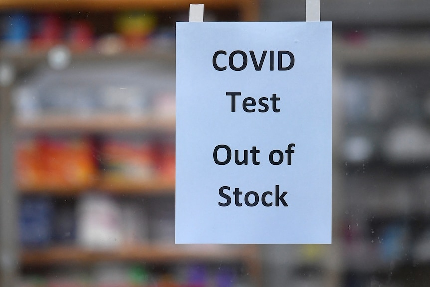 An A4 piece of paper stuck to a window reads: "COVID Test Out of Stock". 