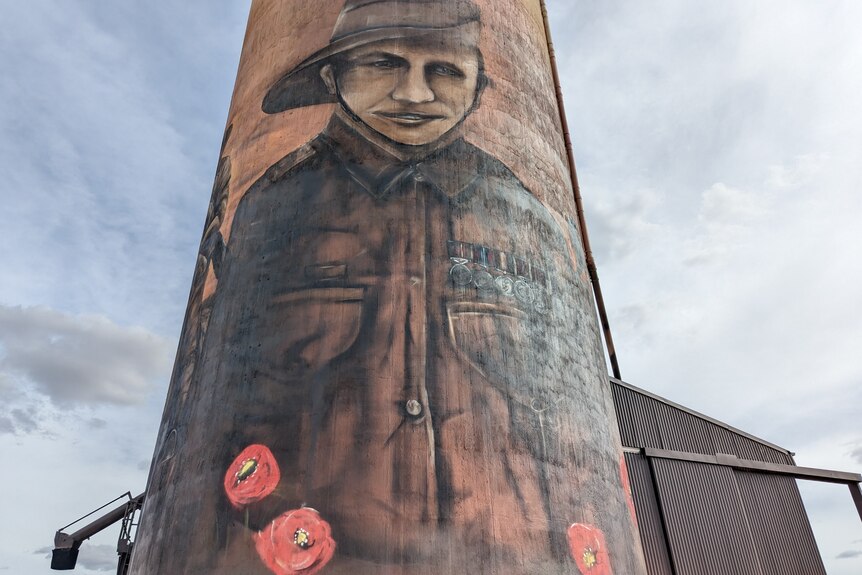 A portrait of returned soldier Tom Zilm on a huge silo surrounded by red poppies.