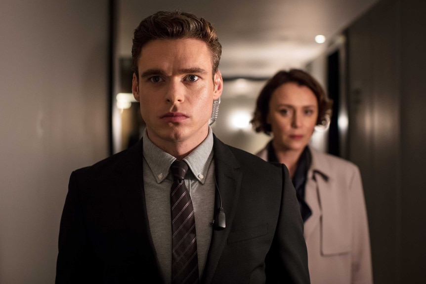 A scene from the tv show Bodyguard with the bodyguard in the foreground and his client in the background