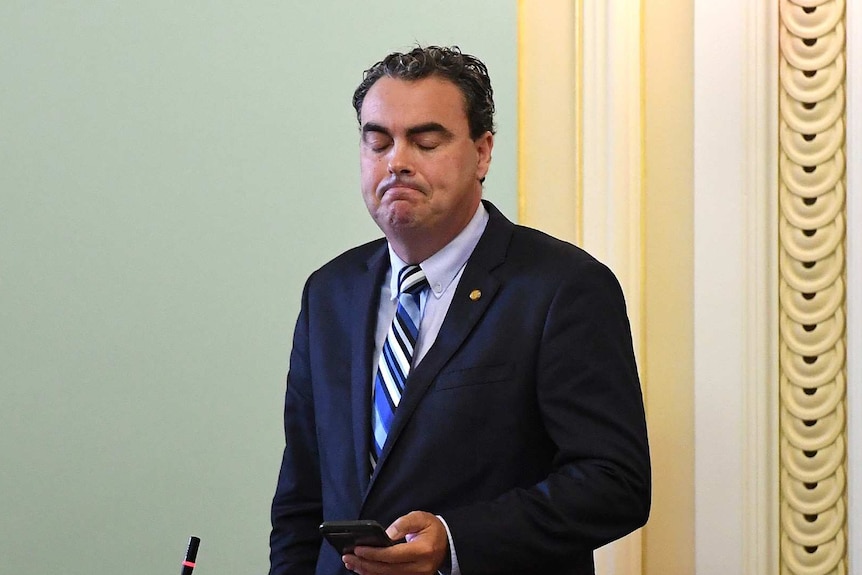 A man in a suit frowns looking sad.