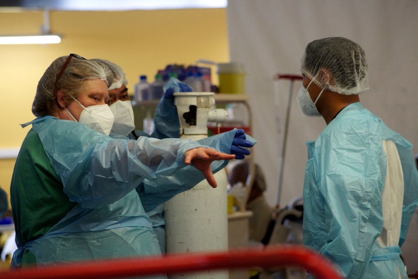 Несколько медсестер разговаривают в СИЗ в больничной палате
