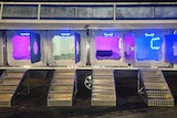 A trailer with six individual compartments are illuminated by blue and purple light.