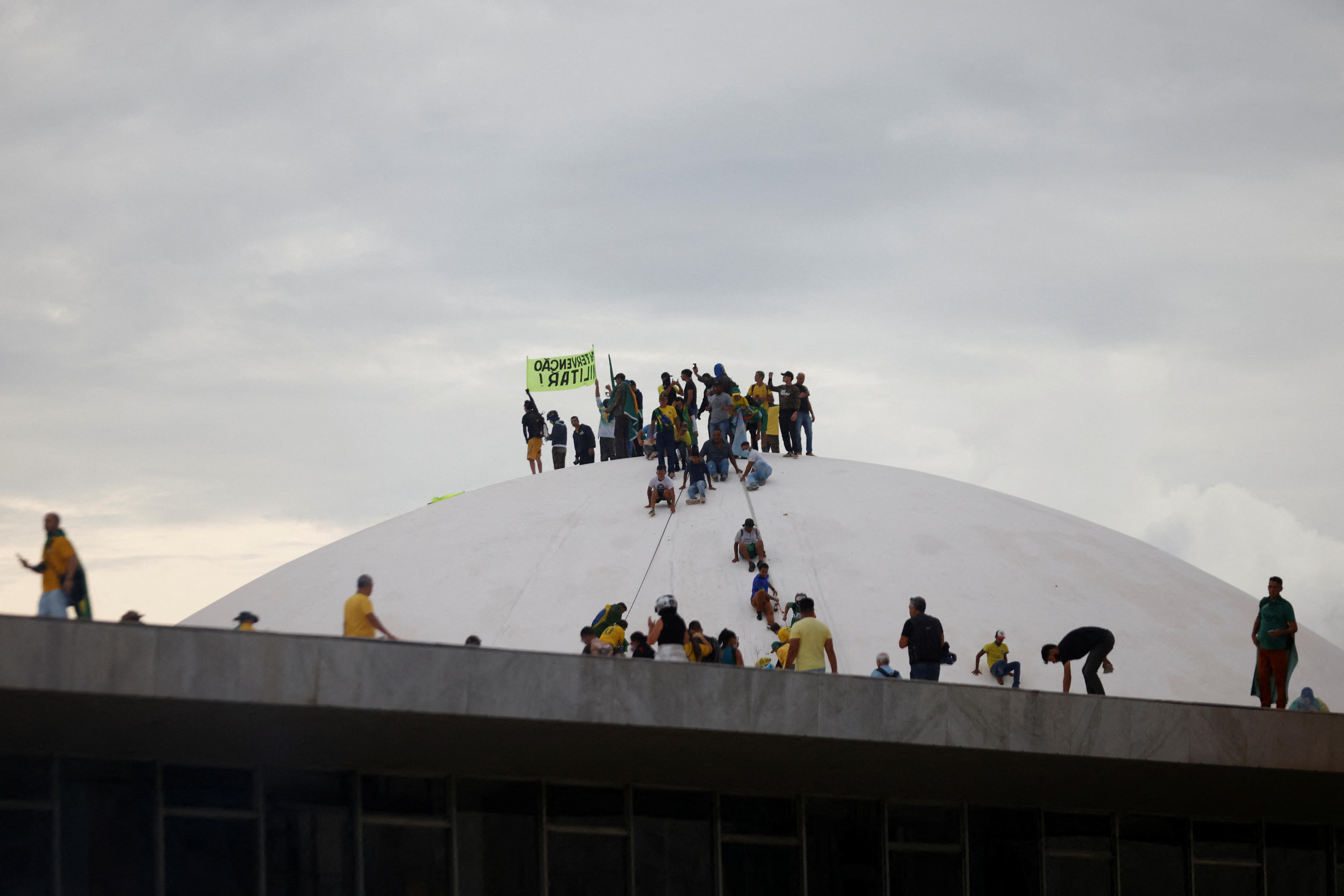 A group of people wearing yellow shits sit on top of a white dome