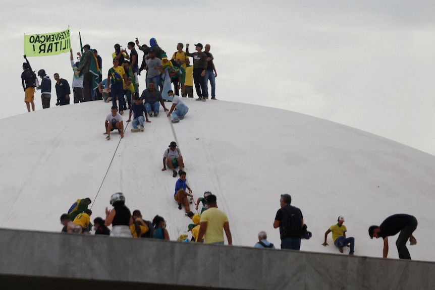 A group of people wearing yellow shits sit on top of a white dome