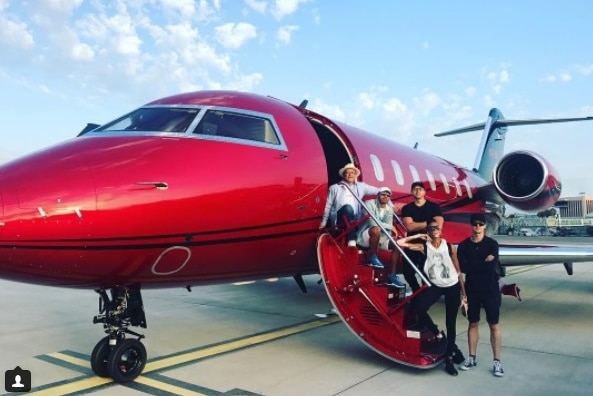 Lewis Hamilton and friends pose on the stairs of his private jet.
