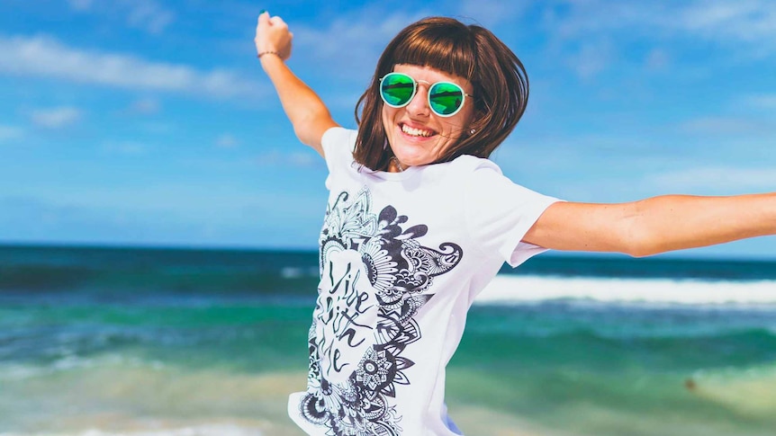 Happy woman wearing sunglasses smiling on a sunny beach to depict getting the most out of summer holidays and leave.