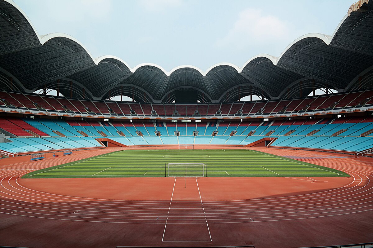 An ultrawide colour photograph of a athletics track and soccer pitch inside Rungrado May Day Stadium in Pyongyang on a clear day