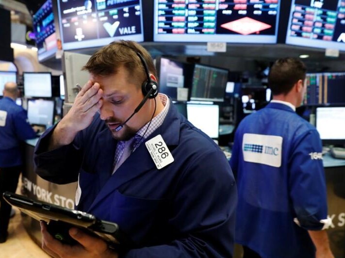 Wall Street trader holds his head, looking disappointed.