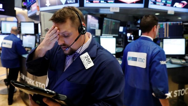 Wall Street trader holds his head, looking disappointed.