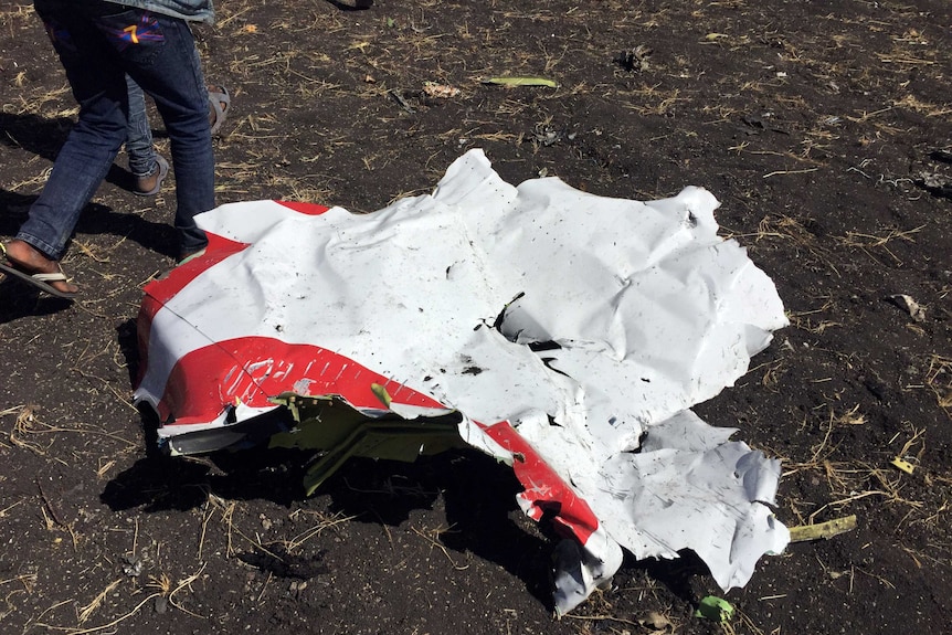 People walk past a part of the wreckage at the scene of the crash.