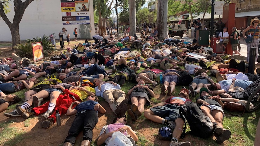 A crowd of people lie on the ground near an Alice Springs mall as part of a 'die-in' protest.