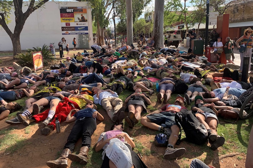 A crowd of people lie on the ground near an Alice Springs mall as part of a 'die-in' protest.