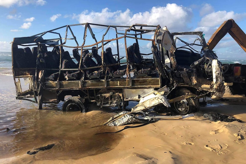 The shell of a tour bus that was stranded on a beach