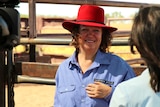 Gina Rinehart smiles while standing in front of cattle pens