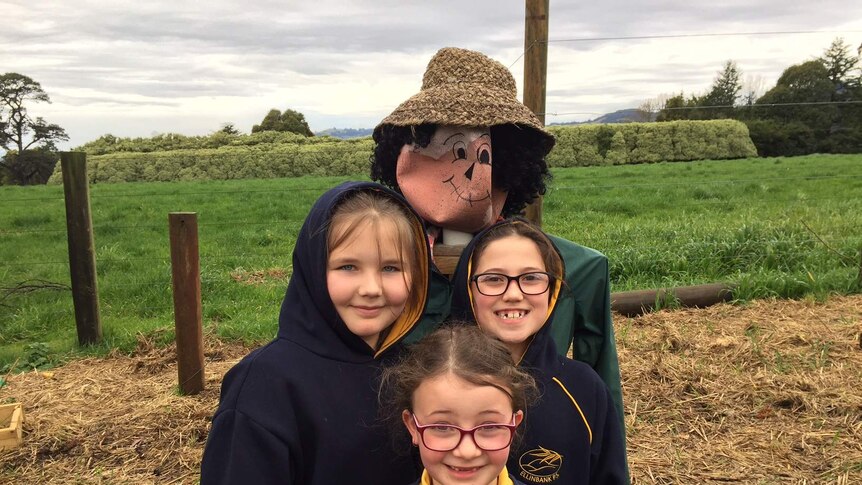 Three students from the Ellinbank Primary School are pictured with a scarecrow in the school garden.