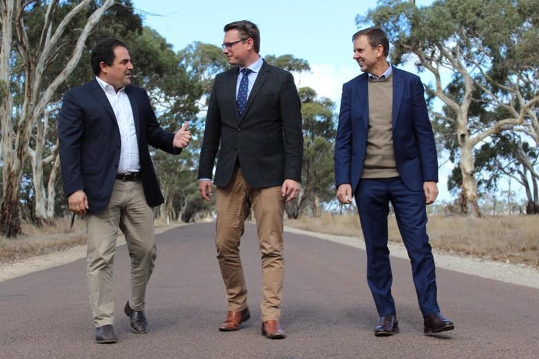 Three men in chinos and blazers on a road