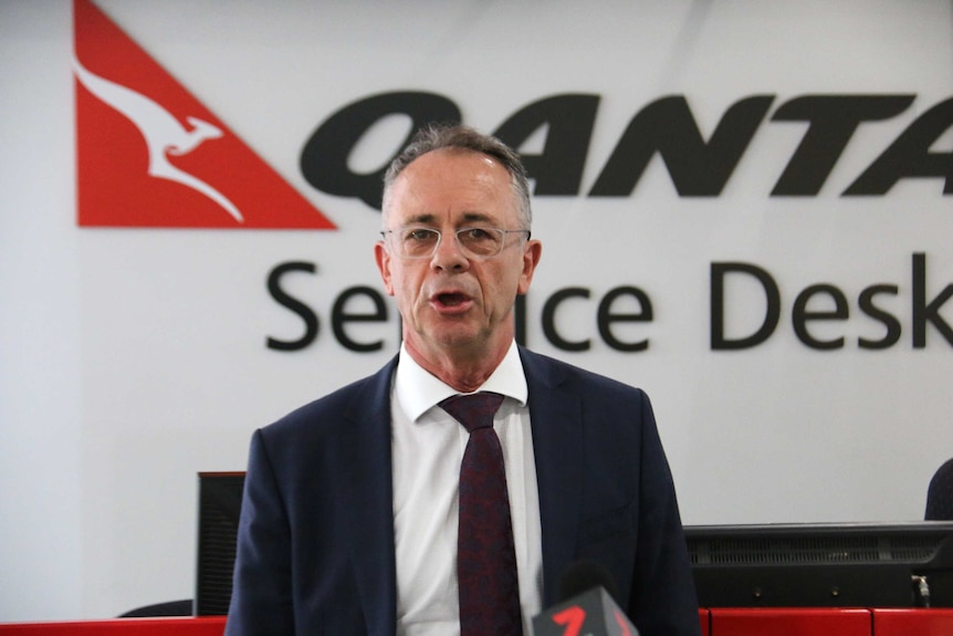 A mid shot of CEO of Qantas Domestic Andrew David in front of a wall adorned with the airline logo.
