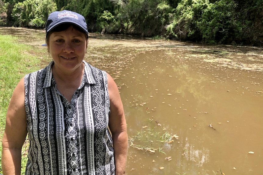 Roz Mercer smiles at the camera with a full waterhole behind her.