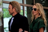Craig McLachlan walks into court with his partner Vanessa Scammell holding his arm.