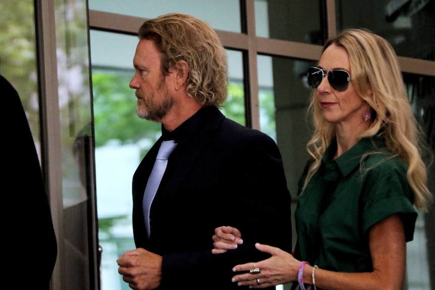 Craig McLachlan walks into court with his partner Vanessa Scammell holding his arm.